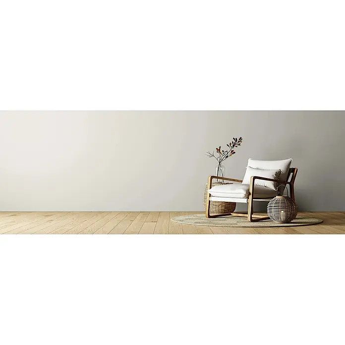 Caleo Color Wandfarbe Lehmfarbe Raureif - Raureif, Matt, 10 l - Ein heller Holz-Sessel mit weißen Kissen steht auf einem runden Teppich in einem minimalistischen Raum mit geflochtenem Dekor.