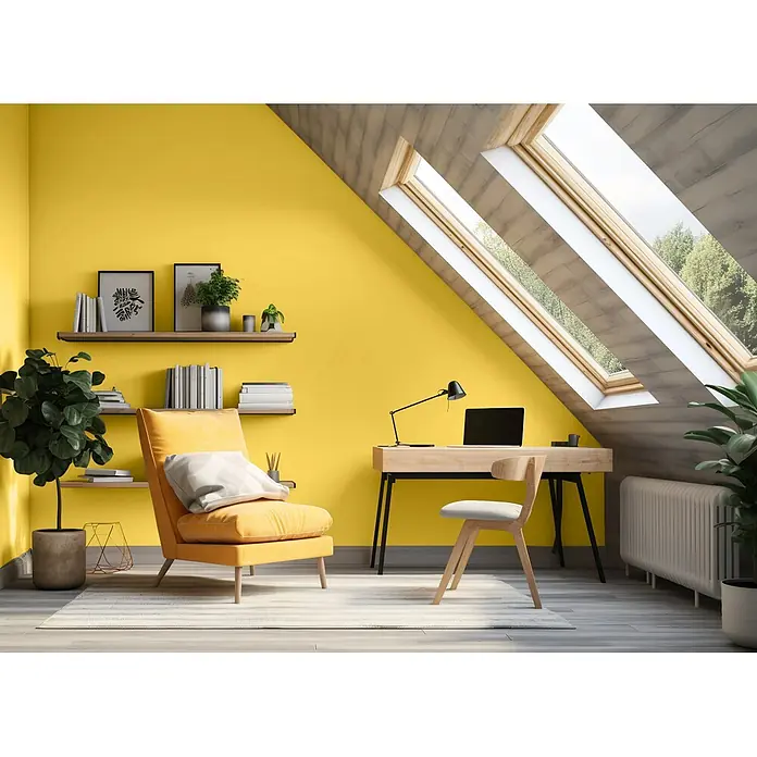 Caleo Color Wandfarbe Lehmfarbe Goldregen - Goldregen, Matt, 0,15 l - Helles gelbes Dachzimmer mit Holzschreibtisch, Stuhl und Sessel, Regale mit Büchern und Pflanzen, durch Oberlichter beleuchtet.