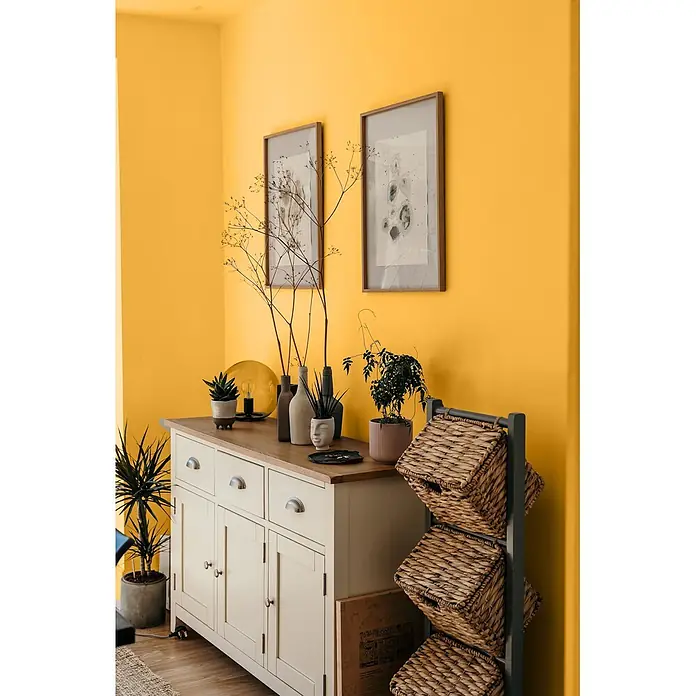 Caleo Color Wandfarbe Lehmfarbe Bienenwabe - Bienenwabe, Matt, 5 l - Cremeweiße Holzkommode mit Metallgriffen und Holzplatte, daneben ein dunkelgraues Regal mit geflochtenen Körben.