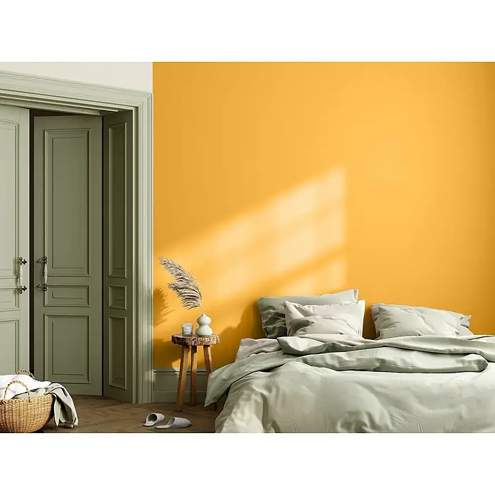 Caleo Color Wandfarbe Lehmfarbe Bienenwabe - Bienenwabe, Matt, 5 l - Salbeigrünes Bettwäsche und Kissen auf einem Bett in einem Schlafzimmer mit grünen Türen und einer gelben Wand.