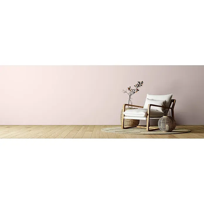 Caleo Color Wandfarbe Lehmfarbe Blütenpracht - Blütenpracht, Matt, 0,15 l - Ein minimalistischer Sessel mit hellem Holzrahmen und weißen Kissen, eingerichtet in einem Raum mit natürlichen Akzenten, inklusive Vase mit Ästen und geflochtener Deko.