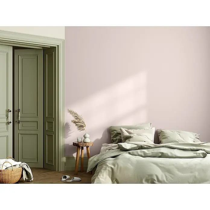 Caleo Color Wandfarbe Lehmfarbe Blütenpracht - Blütenpracht, Matt, 0,15 l - Ein gemütliches Bett mit hellgrüner Bettwäsche in einem Schlafzimmer mit zartrosa Wänden und klassischen grünen Türen.