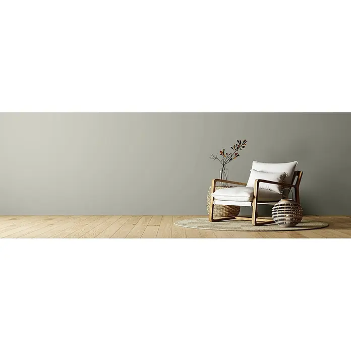 Caleo Color Wandfarbe Lehmfarbe Rauchschwade - Rauchschwade, Matt, 2,25 l - Ein moderner Wohnraum mit einer hellen salbeigrünen Wand, einem Holz-Sessel mit weißen Kissen und natürlichen Flecht-Dekoelementen.
