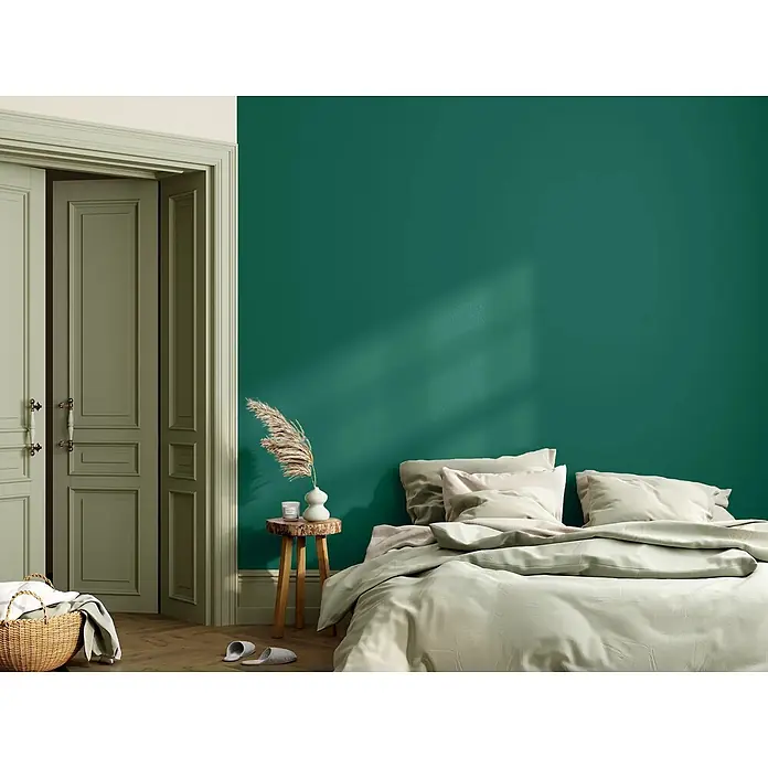 Caleo Color Wandfarbe Lehmfarbe Palmenblatt - Palmenblatt, Matt, 2,25 l - Gemütliches Schlafzimmer mit leuchtend grüner Wand, hellbeiger Bettwäsche, rustikalem Holztischchen und offenen salbeigrünen Türen.