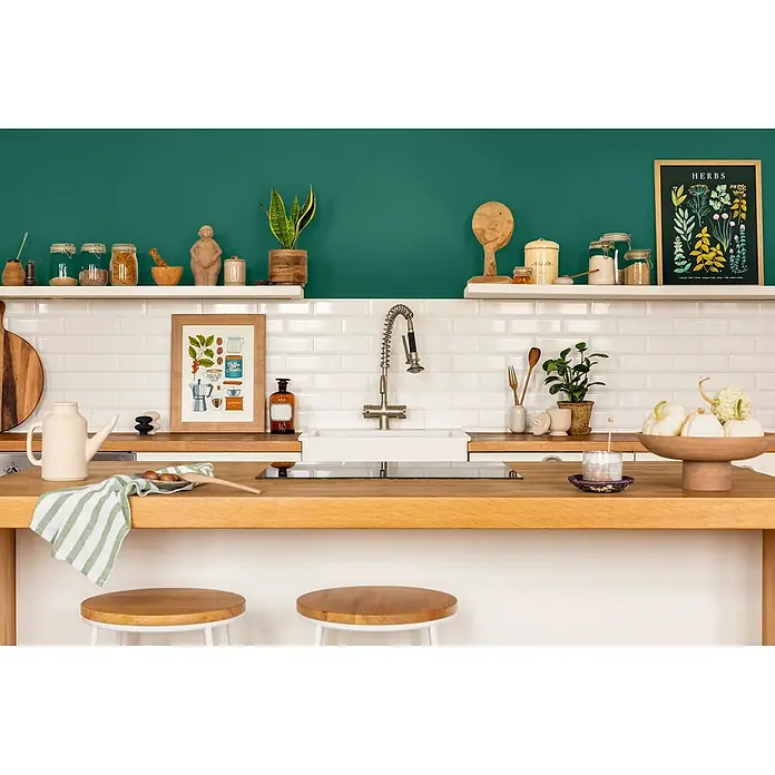 Caleo Color Wandfarbe Lehmfarbe Palmenblatt - Palmenblatt, Matt, 2,25 l - Eine moderne Küche mit grüner Wand, weißen Metrofliesen und Holzmöbeln, dekoriert mit Küchenutensilien.