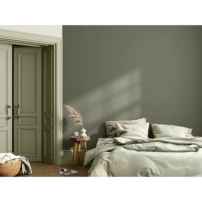 Caleo Color Wandfarbe Lehmfarbe Rosmarin - Rosmarin, Matt, 5 l - Schlafzimmer mit salbeigrünen Wänden, hellgrüner Bettwäsche und passender Tür. Mit Holztischchen und Korb.