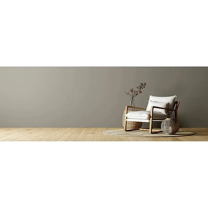 Caleo Color Wandfarbe Lehmfarbe Mangrovenwald - Mangrovenwald, Matt, 2,25 l - Ein moderner Akzentsessel mit hellem Holzrahmen und weißen Kissen, inszeniert mit natürlichen Korbelementen in einem minimalistischen Raum.