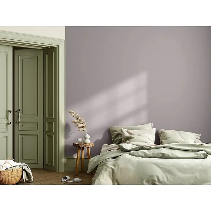 Caleo Color Wandfarbe Lehmfarbe Achat - Achat, Matt, 5 l - Ein Schlafzimmer mit Bett in Hellgrün, lila Wand und salbeigrünen Türen. Ein Holznachttisch steht neben dem Bett.