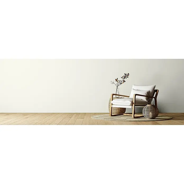 Caleo Color Wandfarbe Lehmfarbe Weiß - Weiß, Matt, 10 l - Moderner Sessel mit weißen Polstern und Holzrahmen in gemütlicher Zimmereinrichtung mit Pflanze und geflochtenen Accessoires.