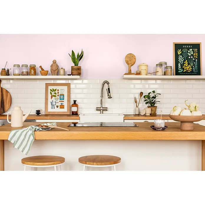 Caleo Color Wandfarbe Lehmfarbe Zuckerwatte - Zuckerwatte, Matt, 2,25 l - Eine helle, moderne Küche mit hellem Holz, weißen Fliesen, offenen Regalen und verschiedenen Küchenartikeln.