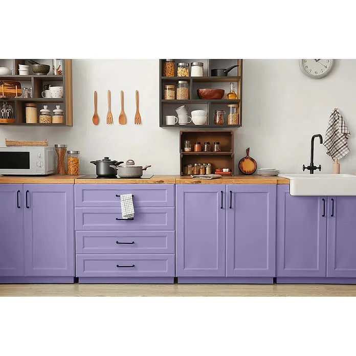 Caleo Color Buntlack Veilchenblüte - Veilchenblüte, Seidenmatt, 0,15 l, Wasserbasiert - Eine moderne Küche mit leuchtend violetten Unterschränken, hellen Holz-Arbeitsplatten und offenen Regalen voller Gläser und Utensilien.
