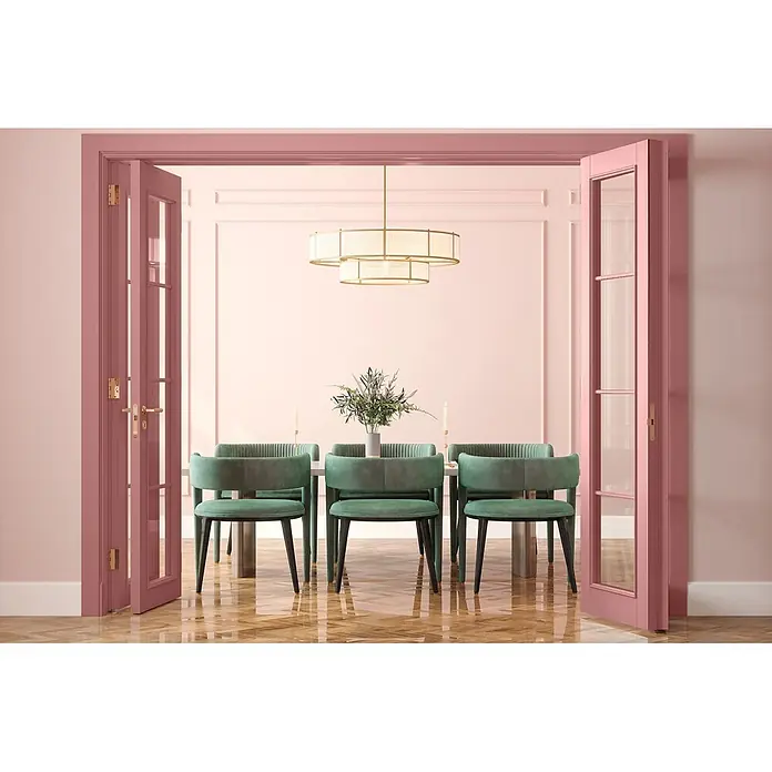 Caleo Color Buntlack Rosenquarz - Rosenquarz, Seidenmatt, 0,15 l, Wasserbasiert - Elegantes Esszimmer mit rosa Wänden, sichtbar durch offene rosa Türen. Grüne Samtstühle und ein goldener Kronleuchter.
