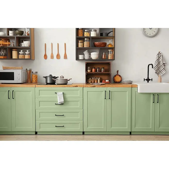 Caleo Color Buntlack Salbeiduft - Salbeiduft, Seidenmatt, 0,68 l, Wasserbasiert - Eine moderne Küche mit hellgrünen Unterschränken, schwarzen Griffen, einer Naturholz-Arbeitsplatte und offenen Regalen darüber.