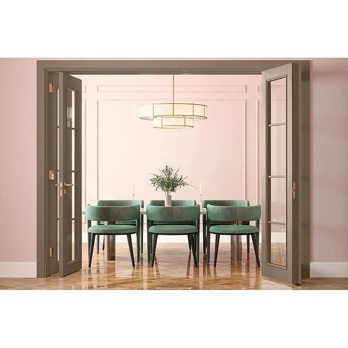 Caleo Color Buntlack Steineiche - Steineiche, Seidenmatt, 0,15 l, Wasserbasiert - Elegantes Esszimmer mit grünen Samtstühlen an einem weißen Tisch, beleuchtet von einem goldenen Kronleuchter, durch offene taupefarbene Türen gesehen.