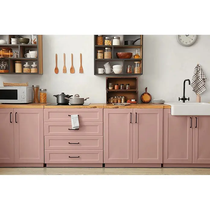 Caleo Color Buntlack Magnolie - Magnolie, Seidenmatt, 0,15 l, Wasserbasiert - Eine moderne Küche mit rosa Schränken, Holztheken und offenen Regalen, ausgestattet mit Kochutensilien und Geräten.