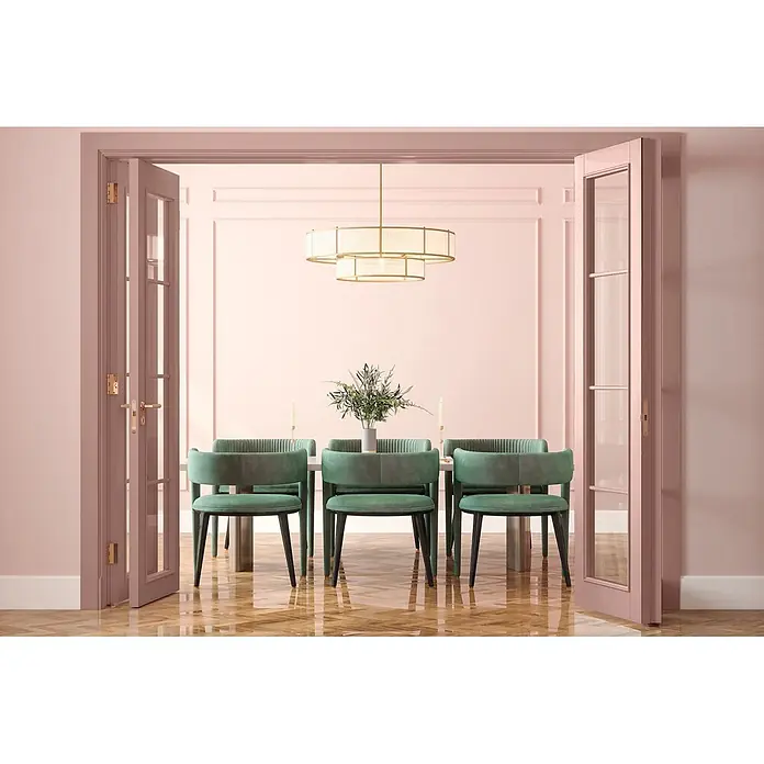 Caleo Color Buntlack Magnolie - Magnolie, Seidenmatt, 0,15 l, Wasserbasiert - Gestufter goldener Kronleuchter und smaragdgrüne Esszimmerstühle in einem rosa Esszimmer.