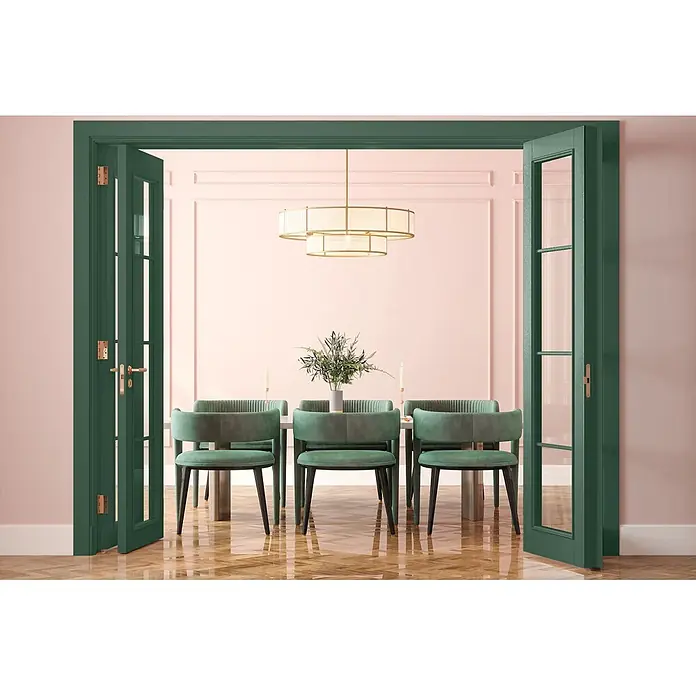Caleo Color Buntlack Feigenblatt - Feigenblatt, Seidenmatt, 0,68 l, Wasserbasiert - Elegantes Esszimmer mit grünen Samtstühlen, weißem Tisch, goldener Kronleuchter, umrahmt von offenen grünen Flügeltüren mit Messingbeschlägen.