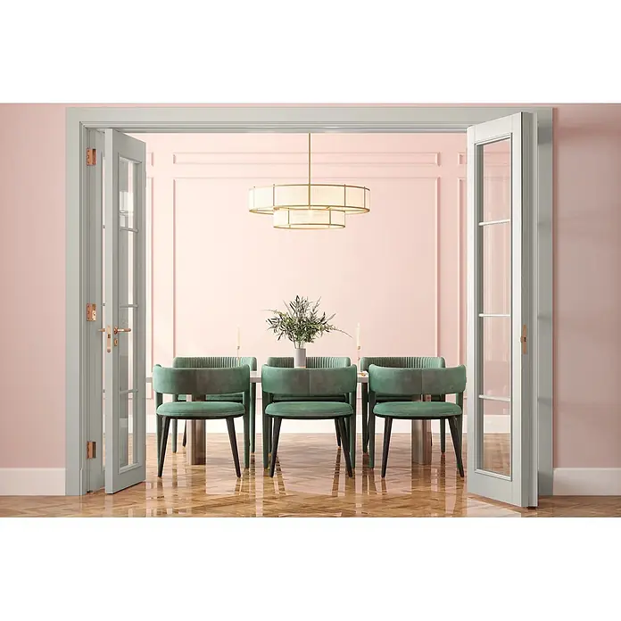 Caleo Color Buntlack Raureif - Raureif, Seidenmatt, 0,15 l, Wasserbasiert - Ein elegantes Esszimmer mit langem Tisch, sechs grünen Samtstühlen, rosa Paneelwänden, einem Stufenkronleuchter und französischen Türen.