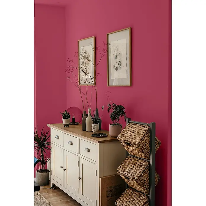 Caleo Color Wandfarbe Lehmfarbe Drachenglut - Drachenglut, Matt, 5 l - Cremefarbenes Sideboard mit Holzplatte, Bilderrahmen & Aufbewahrungseinheit mit Weidenkörben in farbenfrohem Raum.