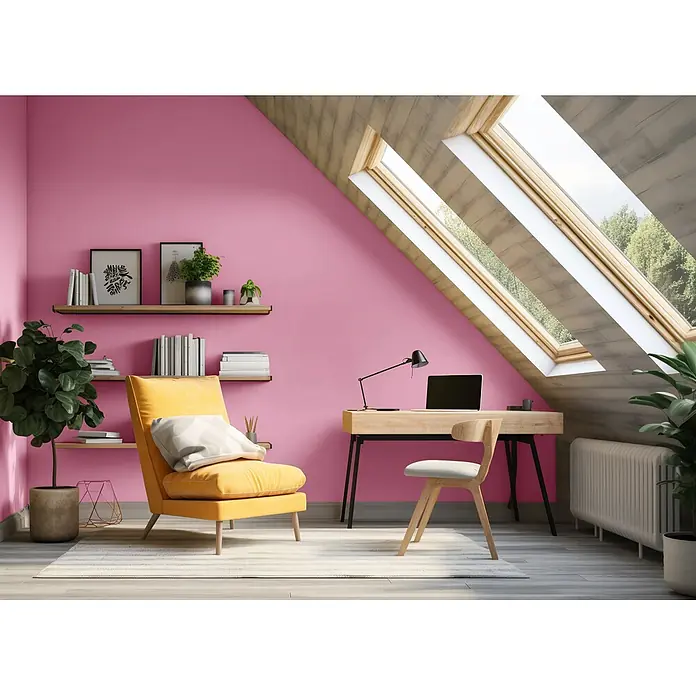 Caleo Color Wandfarbe Lehmfarbe Himbeere - Himbeere, Matt, 2,25 l - Ein lebhaftes rosafarbenes Dachzimmer mit gelbem Sessel, Holzschreibtisch und Dachfenstern, schafft einen hellen, gemütlichen Arbeitsbereich.