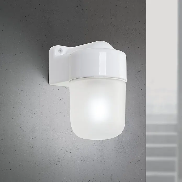 Orion Leuchten Wandleuchte - 40 W, L x B x H: 11,2 x 8,5 x 14,6 cm, E27 - Weiße Wand-Außenleuchte mit mattierter Abdeckung, leuchtend an einer Betonwand.
