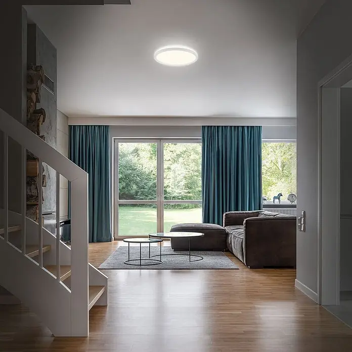 Brilo Plafón LED redondo Slim Case - 18 W, Ø x Al: 29 x 3 cm, Blanco, Blanco neutro - Un plafón redondo y blanco brillante ilumina una sala de estar moderna.
