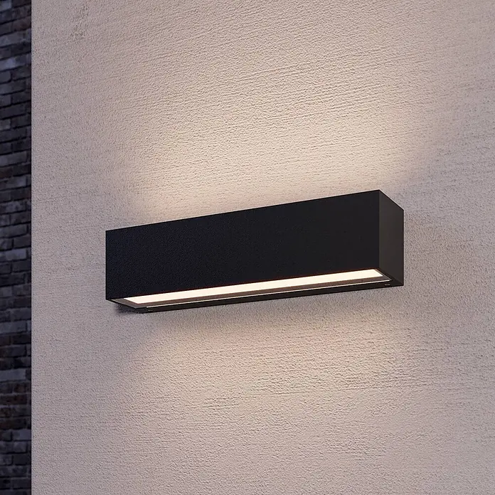 Lucande LED Wandlampe aussen grafitgrau, LED Wandleuchte außen, -  - Schwarze rechteckige Außenwandleuchte mit strukturierter Oberfläche, die warmes Auf-/Ablicht auf eine strukturierte Wand wirft.