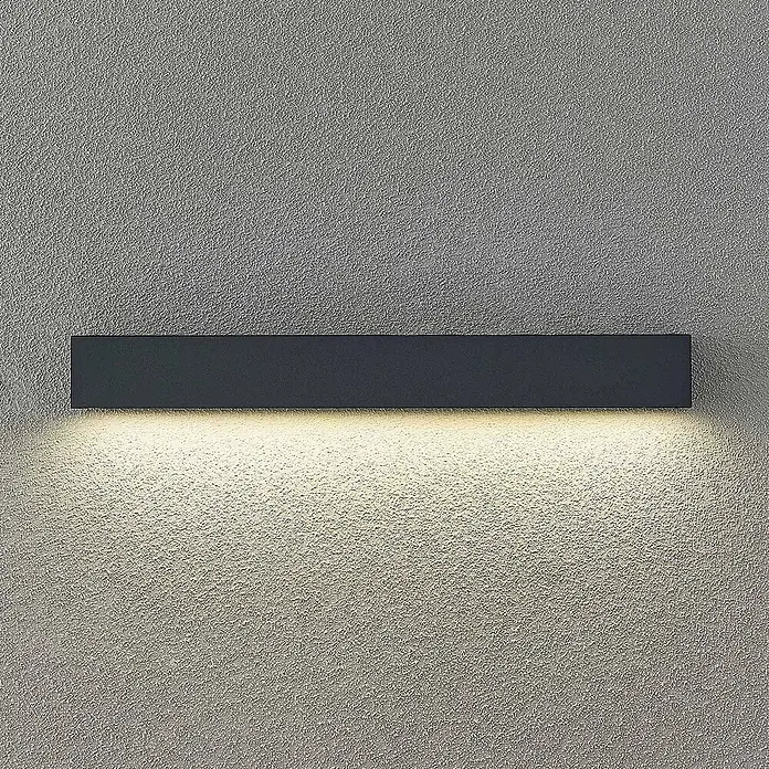 Arcchio LED Wandleuchte aussen in anthrazit, Aussenlampe Wand -  - Dunkelgraue rechteckige Wandleuchte beleuchtet eine strukturierte Wand mit warmweißem Licht.