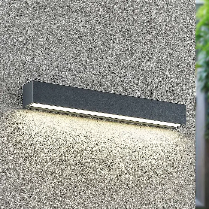 Arcchio LED Wandleuchte aussen in anthrazit, Aussenlampe Wand -  - Dunkelgraue, rechteckige Außenwandleuchte, die warmes Licht nach unten auf eine strukturierte Wand wirft.