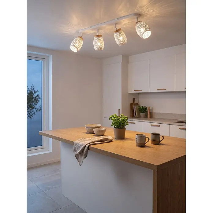 Reality Leuchten Bidar Regleta - 40 W, L x An x Al: 12 x 74 x 27 cm, Blanco, Blanco, E14, 4 ud. - Cuatro focos de techo blancos con pantallas de patrón geométrico y detalles de madera iluminan una isla de cocina moderna.