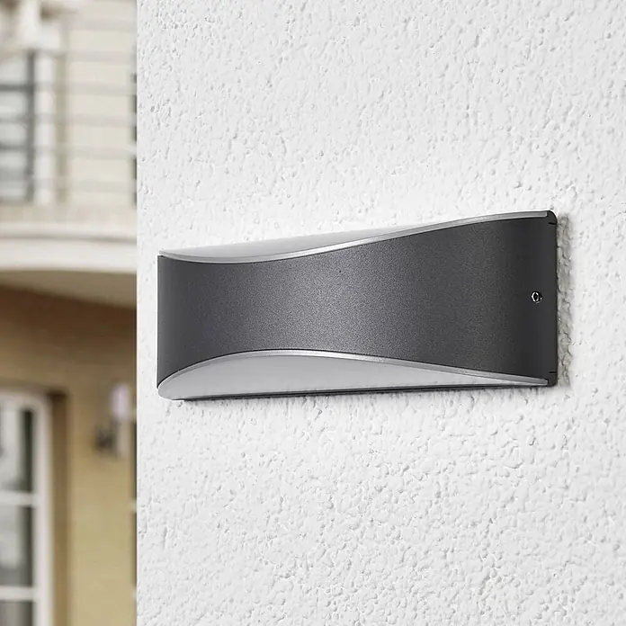 Lucande LED Wandleuchte aussen in anthrazit, weiß satiniert, up down -  - Dunkelgraue, geschwungene Außenwandleuchte mit silbernen Akzenten, an einer strukturierten weißen Außenwand montiert.