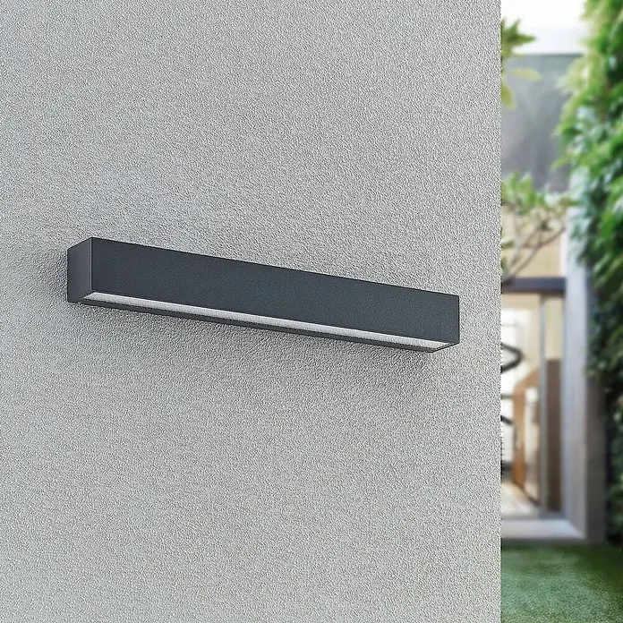 Arcchio LED Wandleuchte aussen in anthrazit, Aussenlampe Wand -  - Dunkelgraue rechteckige LED-Außenwandleuchte an einer strukturierten Wand, die ein sanftes Licht abgibt.