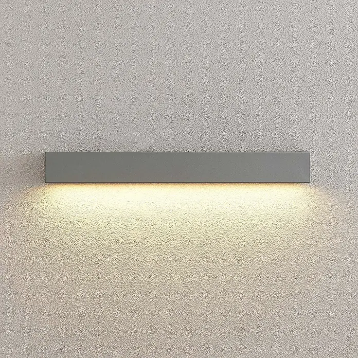 Lucande Außenwandleuchte Lengo - alu / grau / zink, IP65 - Graue rechteckige Wandleuchte, die warmes Licht nach unten auf eine strukturierte Wand wirft.