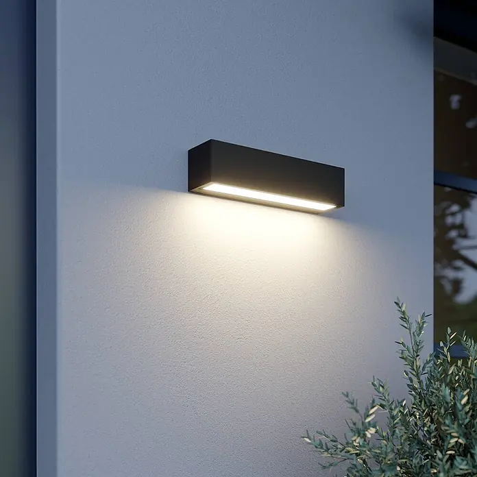 Lucande LED Wandleuchte aussen in anthrazit, Aussenlampe Wand -  - Schwarze rechteckige Außenwandleuchte an einer texturierten Wand, die warmes Licht nach unten wirft.