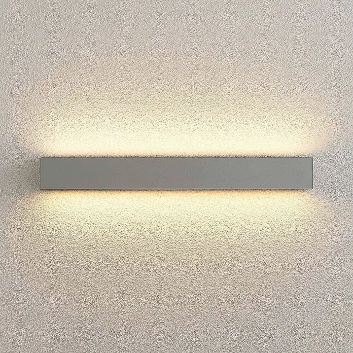 Lucande LED Wandleuchte aussen in silber, Aussenlampe Wand -  - Rechteckige graue LED-Wandleuchte, die warmes Licht nach oben und unten auf eine strukturierte Wand wirft.