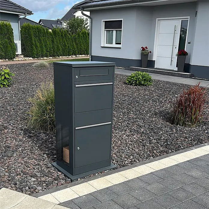 Metzler Paketbox BRFK BISPO SF - L x B x H: 37 x 50,2 x 112 cm, Anthrazit, Stahl, Paketfach, Mit Seitenfenster - Dunkelgrauer Paketbriefkasten mit mehreren Fächern, inklusive einem sichtbaren Paket im unteren Klarsichtbereich, im Garten stehend.