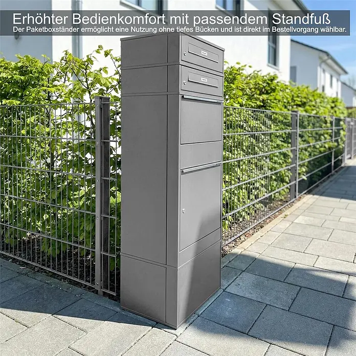Metzler Paketbox 2 BRFK BISPO RE - L x B x H: 37,4 x 50,3 x 130,3 cm, Graualuminium, Stahl, Paketfach, Mit 2 Briefkastenfächern und Namensschildern - Hoher, dunkelgrauer Mehrfach-Paketbriefkasten mit Standfuß auf einem gepflasterten Weg neben einem Metallzaun.