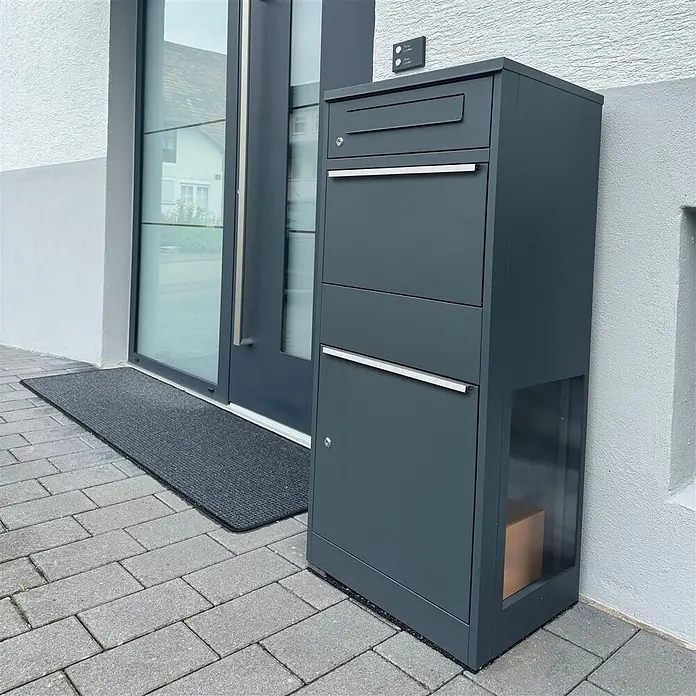 Metzler Paketbox BRFK BISPO SF - L x B x H: 37 x 50,2 x 112 cm, Anthrazit, Stahl, Paketfach, Mit Seitenfenster - Dunkelgrauer, moderner Paketbriefkasten mit mehreren Fächern, eines davon mit sichtbarem Paket, vor einem Hauseingang.