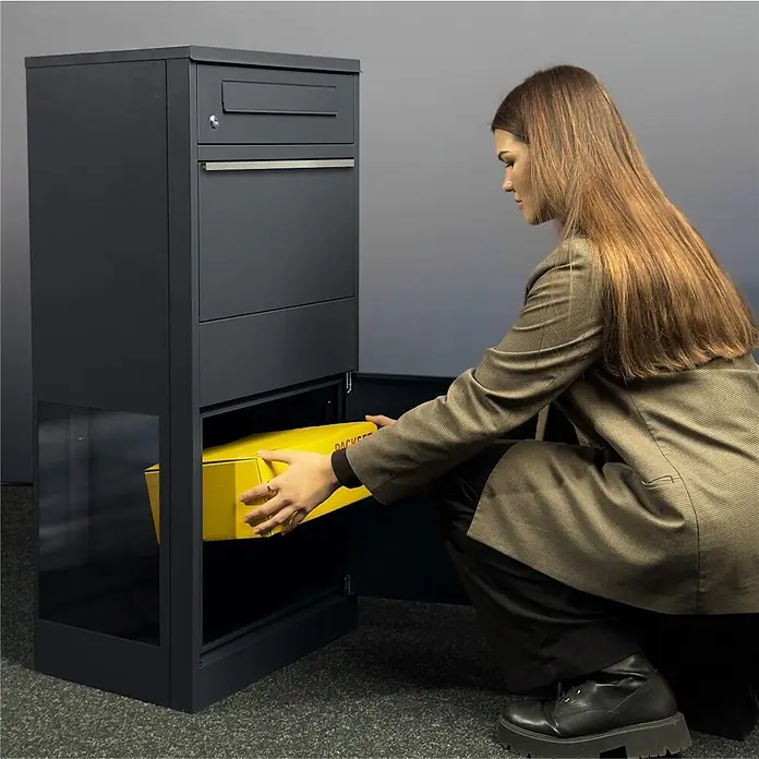 Metzler Paketbox BRFK BISPO SF - L x B x H: 37 x 50,2 x 112 cm, Anthrazit, Stahl, Paketfach, Mit Seitenfenster - Dunkelgraue Paketbox aus Metall; eine Person legt ein gelbes Paket in das untere Fach.