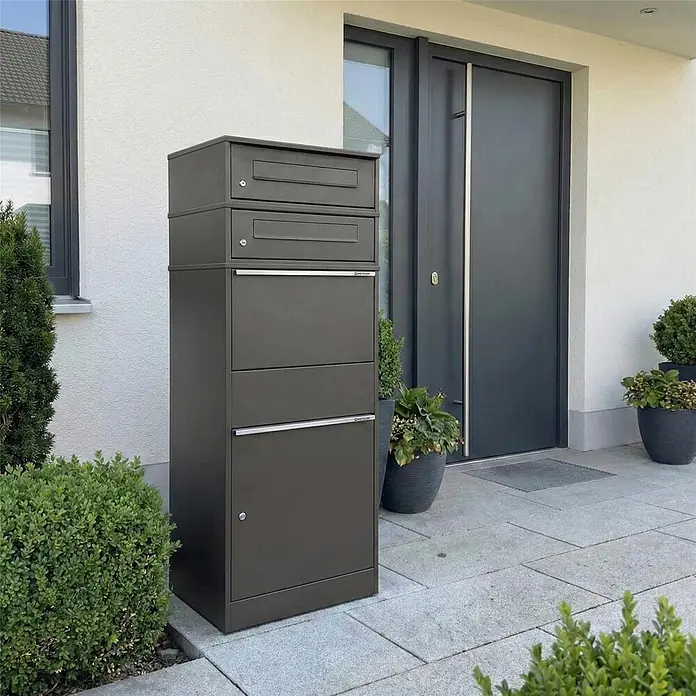 Metzler Paketbox 3 BRFK BISPO - L x B x H: 37,4 x 50,3 x 147,7 cm, Eisenglimmer, Stahl, Paketfach, 3 Briefkastenfächer - Hohe, dunkelgraue Paket- und Briefkastenanlage mit mehreren Fächern an einem modernen Hauseingang für sichere Lieferungen.