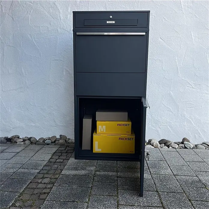 Metzler Paketbox XL BRFK MAX RE - L x B x H: 45,4 x 72 x 145 cm, Anthrazit, Stahl, Paketfach - Dunkelgrauer Paketbriefkasten mit offenem unterem Fach, das gelbe und braune Pakete enthält.