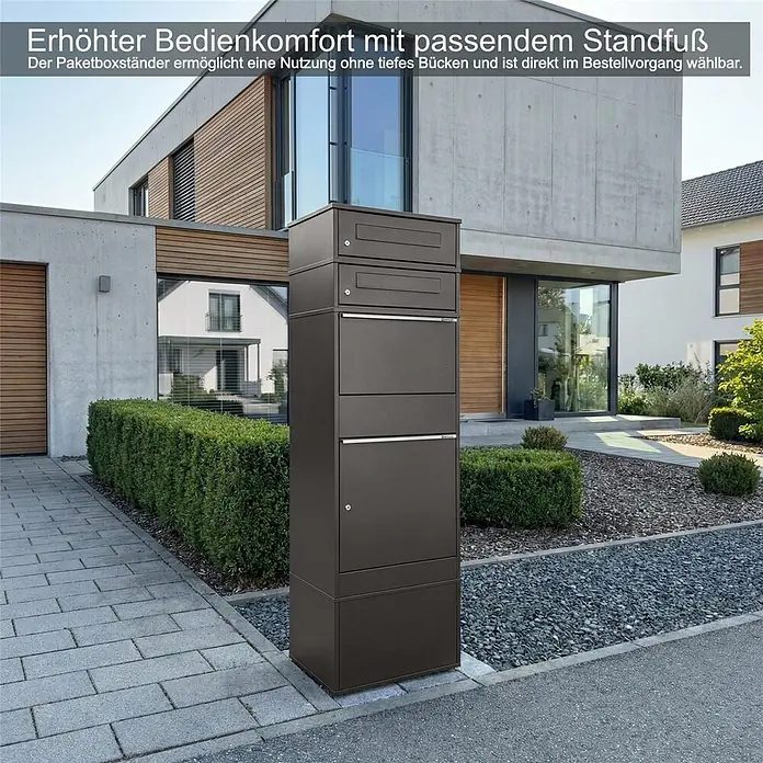 Metzler Paketbox 2 BRFK BISPO - L x B x H: 37,4 x 50,3 x 130,3 cm, Eisenglimmer, Stahl, Paketfach, 2 Briefkastenfächer - Dunkelgrauer Paketkasten-Ständer vor einem modernen Haus, ermöglicht bequemen Paketempfang ohne Bücken.