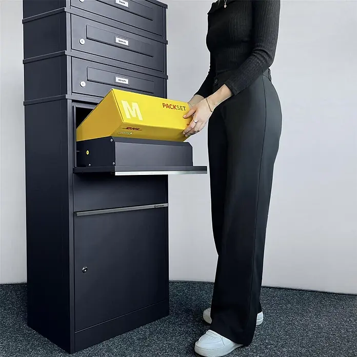Metzler Paketbox 3 BRFK BISPO RE - L x B x H: 37,4 x 50,3 x 147,7 cm, Anthrazit, Stahl, Paketfach, 3 Briefkastenfächer und Namensschildern - Schwarzer Paketbriefkasten, in den eine Person ein gelbes DHL-Paket in das große Fach einlegt.