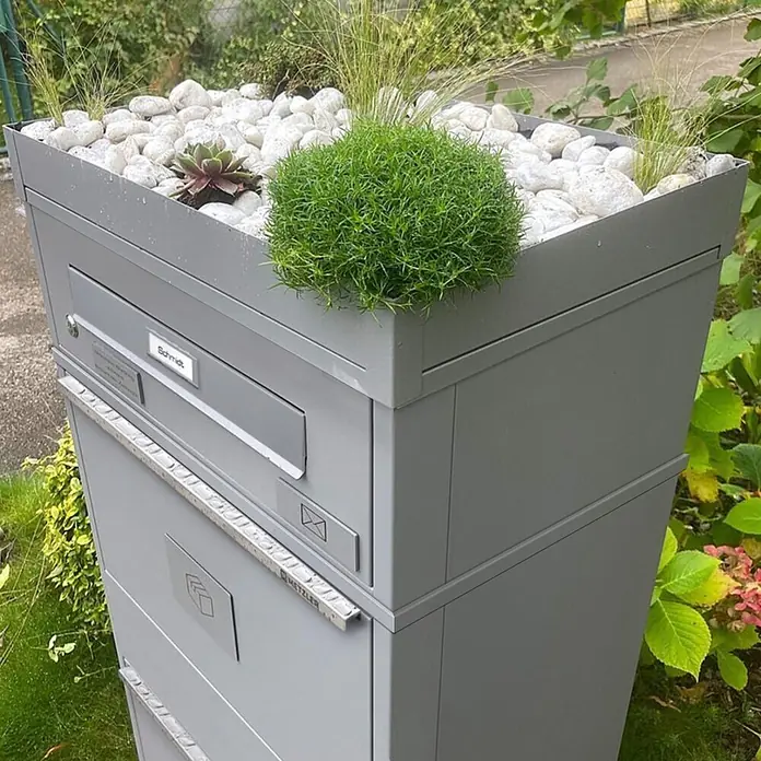 Metzler Paketbox BRFK BISPO RE - L x B x H: 37,4 x 50,3 x 112,9 cm, Graualuminium, Stahl, Paketfach - Ein moderner, grauer Mehrfach-Briefkasten und Paketbox mit integriertem Pflanzgefäß, gefüllt mit Sukkulenten, Gräsern und weißen Kieselsteinen, im Garten.