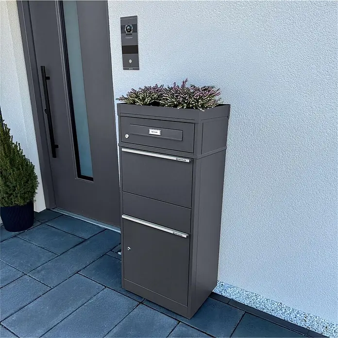 Metzler Paketbox BRFK BISPO RE - L x B x H: 37,4 x 50,3 x 112,9 cm, Eisenglimmer, Stahl, Paketfach - Dunkelgrauer Metall-Paketbriefkasten mit integriertem Pflanzgefäß, an einem modernen Hauseingang.