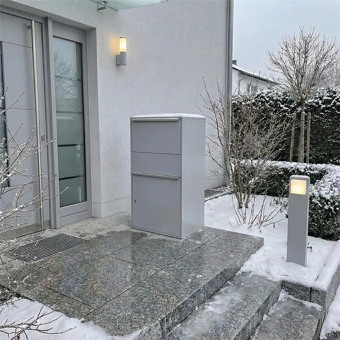 Metzler Paketbox XL BISPO MAX - L x B x H: 45,4 x 72 x 128,5 cm, Graualuminium, Stahl, Paketfach - Große graue Paketbox aus Metall, auf einer verschneiten Granitterrasse am Hauseingang.
