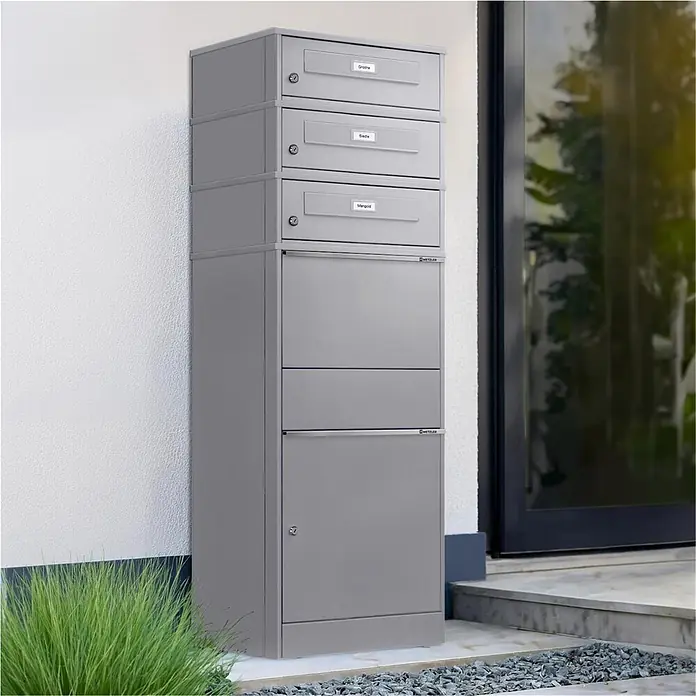 Metzler Paketbox 3 BRFK BISPO RE - L x B x H: 37,4 x 50,3 x 147,7 cm, Graualuminium, Stahl, Namensschild, 3 Briefkastenfächer und Namensschildern - Graue Metall-Briefkastenanlage mit drei Briefschlitzen und zwei Paketfächern, außen neben einem Eingang installiert.