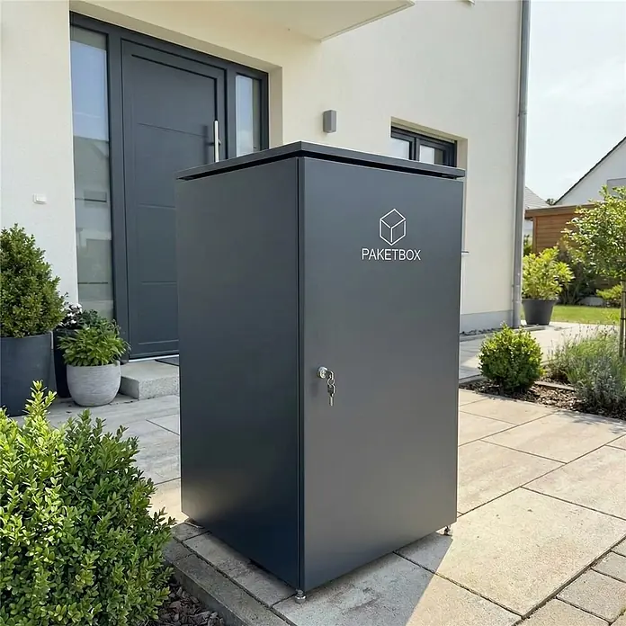 Metzler Paketbox XXL BEN - L x B x H: 81,2 x 68,4 x 123,3 cm, Anthrazit, Stahl - Dunkelgraue Paketbox aus Metall mit Schlüssel im Schloss, vor einem Hauseingang zur sicheren Paketanlieferung.