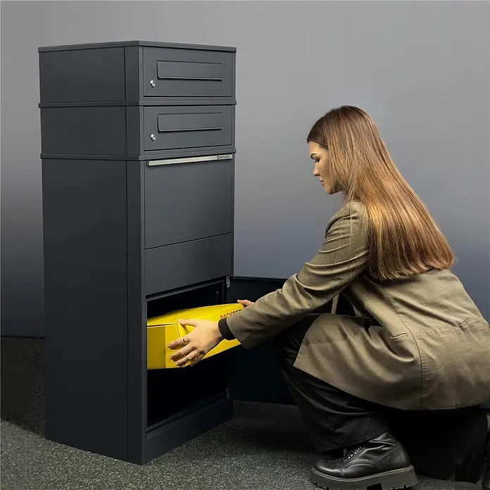 Metzler Paketbox 2 BRFK BISPO - L x B x H: 37,4 x 50,3 x 130,3 cm, Anthrazit, Stahl, Paketfach, 2 Briefkastenfächer - Graue Metall-Paketbox mit mehreren Fächern; eine Frau entnimmt ein gelbes Paket.