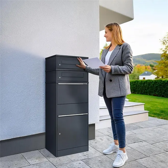 Metzler Paketbox 2 BRFK BISPO - L x B x H: 37,4 x 50,3 x 130,3 cm, Anthrazit, Stahl, Paketfach, 2 Briefkastenfächer - Dunkelgrauer Paketbriefkasten mit mehreren Fächern, eine Frau legt Post ein.